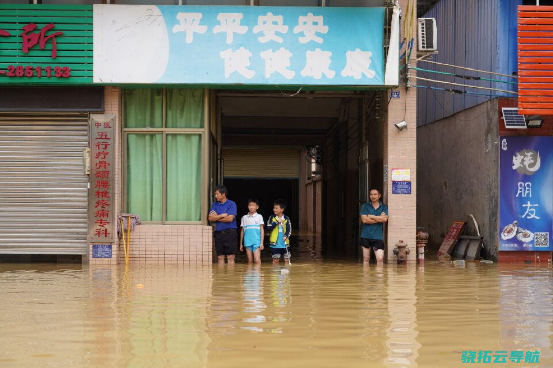 几名群众站在洪水中，水位没过了他们的小腿。